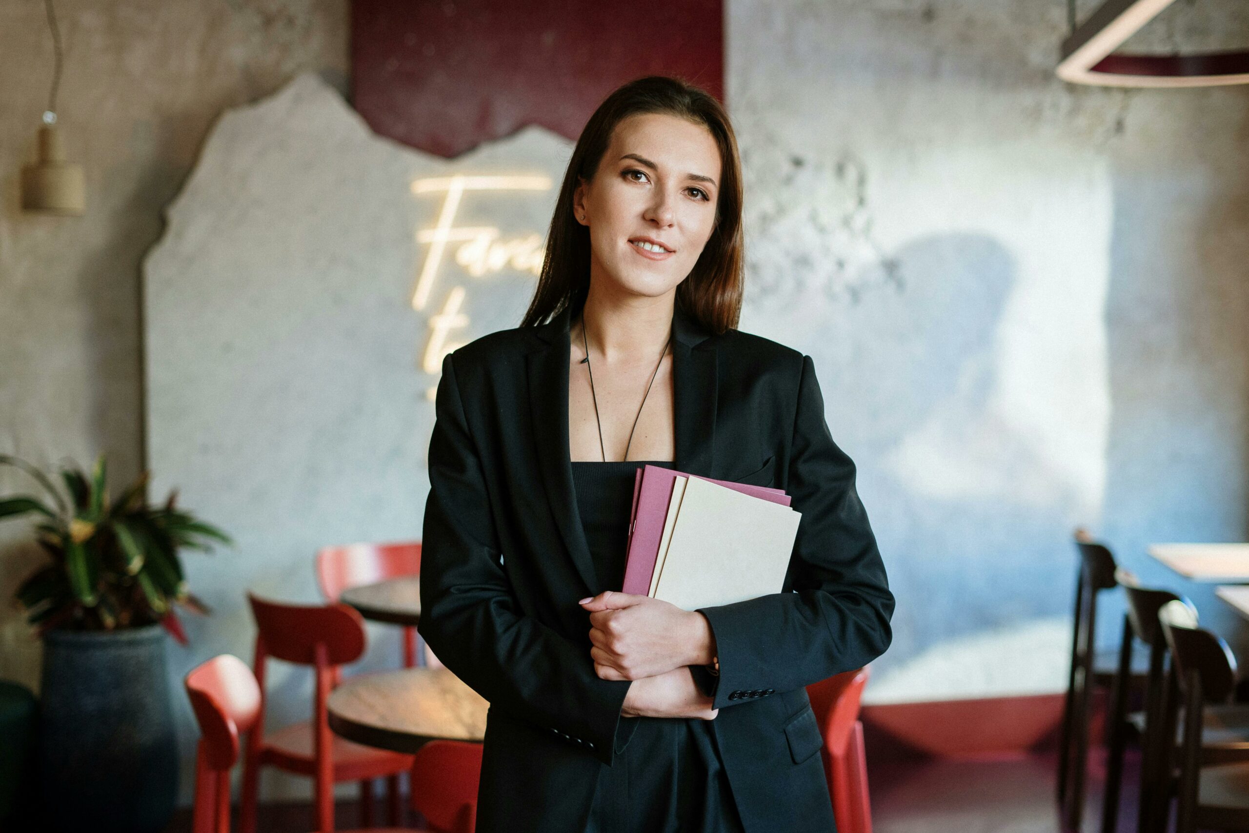 A young woman in a stylish café holding a menu, exuding confidence amidst a chic interior.