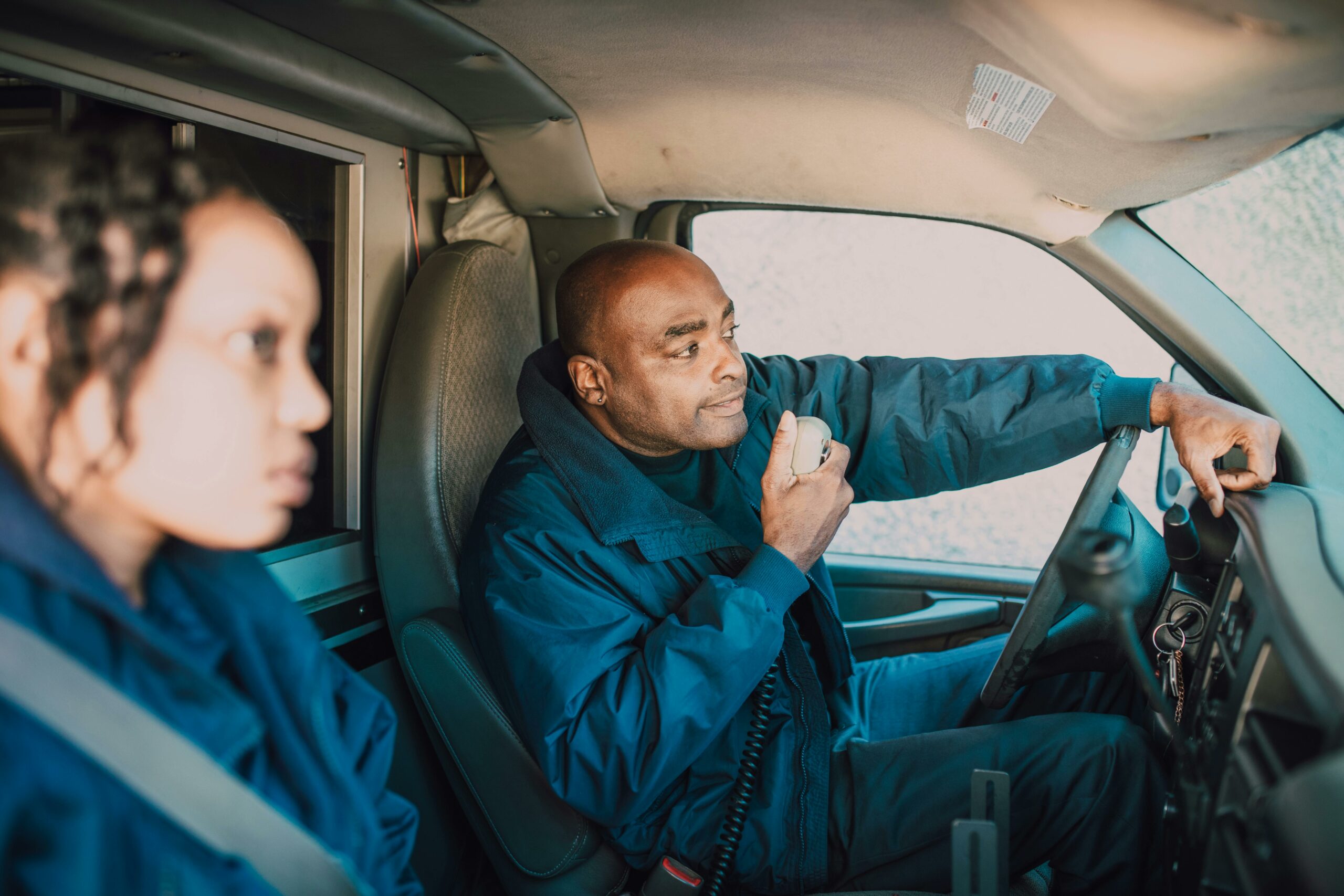 Paramedic team inside ambulance using radio communication equipment.